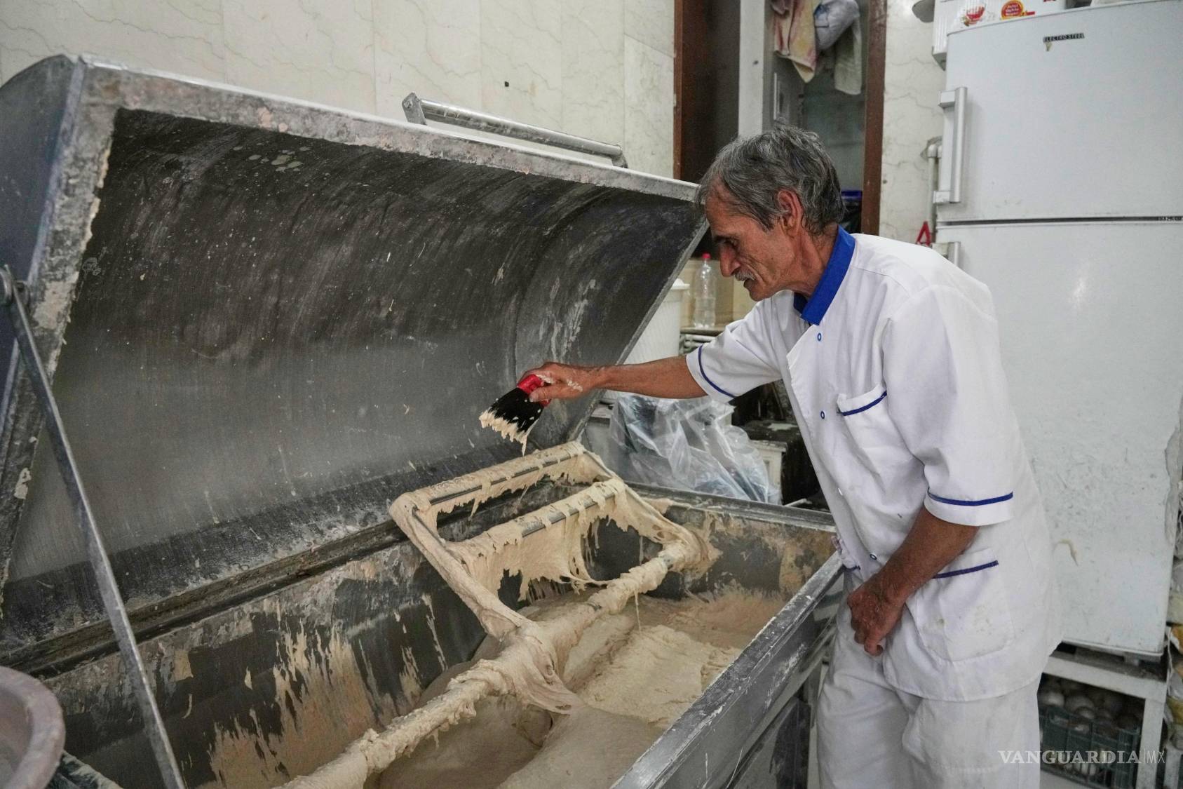 $!Un trabajador manipula la masa utilizada para elaborar sangak, un pan plano tradicional iraní, en una panadería, el martes 18 de agosto de 2026, en Teherán.