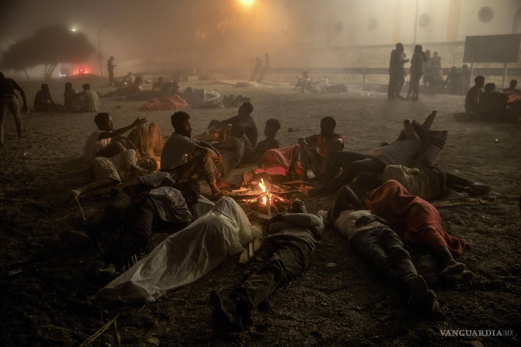 $!Unos hombres aguardan asistencia humanitaria en una playa de Ceuta, un territorio español en el norte de África cuyas fronteras se vieron desbordadas, el 1 de agosto de 2026.