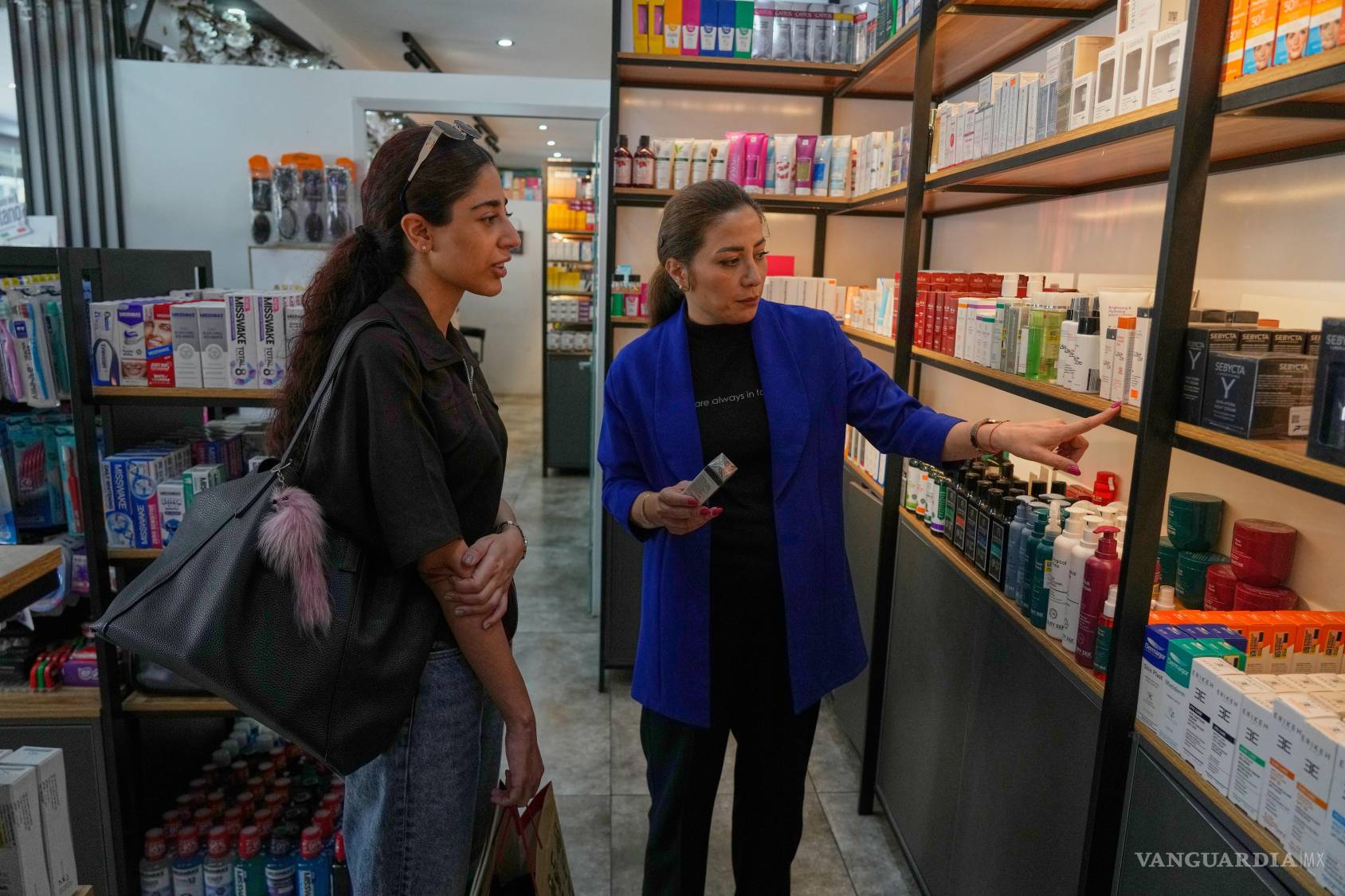 $!La técnica de farmacia Mina Mohammadian habla sobre cosméticos con un cliente en una farmacia de Teherán, Irán.
