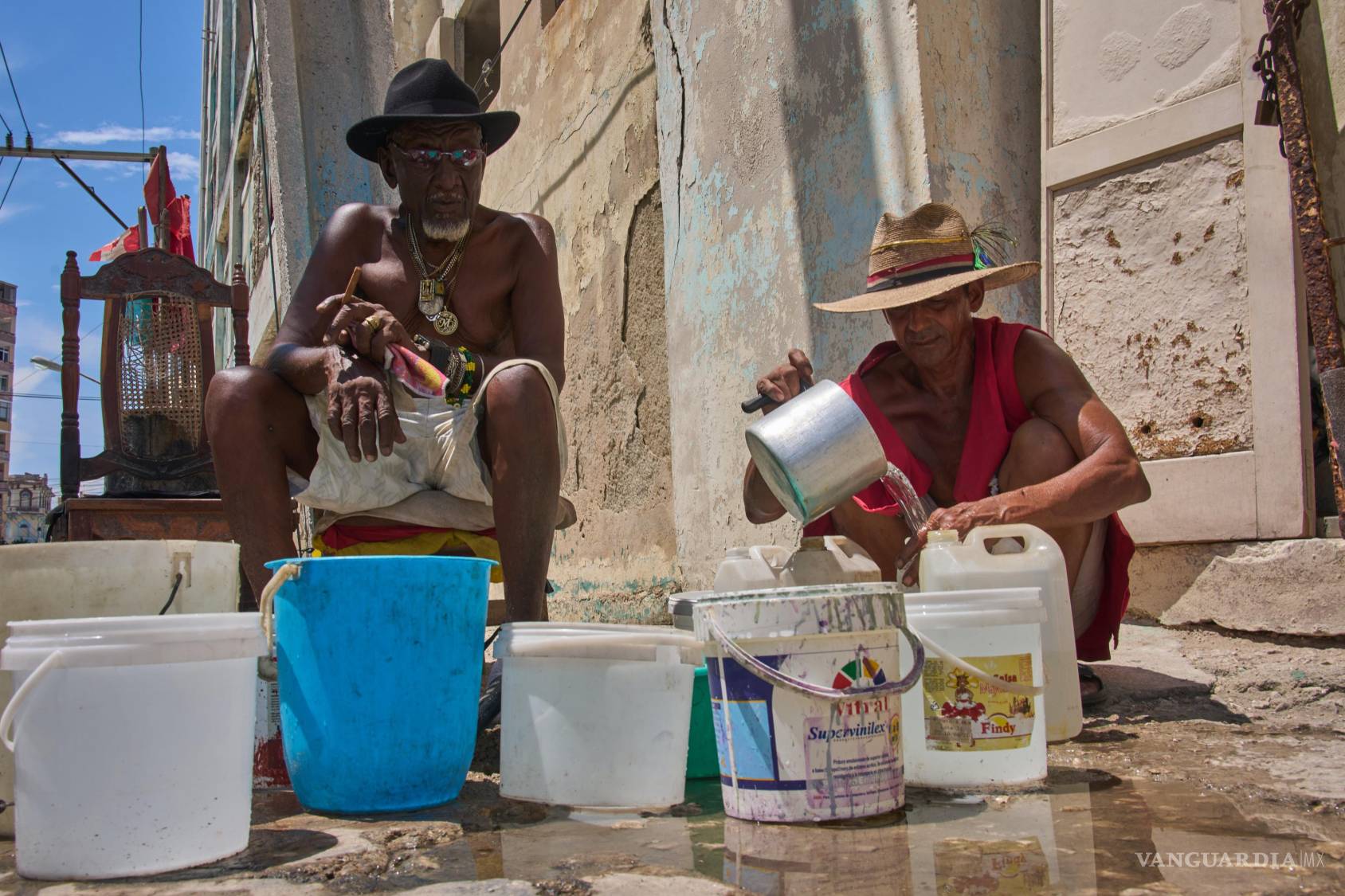 $!Oscar Joaquín López (i) y su compañero de vivienda Wilfredo Cisneros Duarte recogen agua de una tubería callejera en La Habana, Cuba.