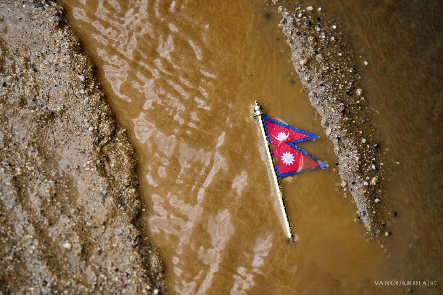 $!Una bandera de Nepal yace en un camino enlodado cerca de la orilla del río Trishuli, en el distrito de Dhading, Nepal, el domingo 30 de agosto de 2026.