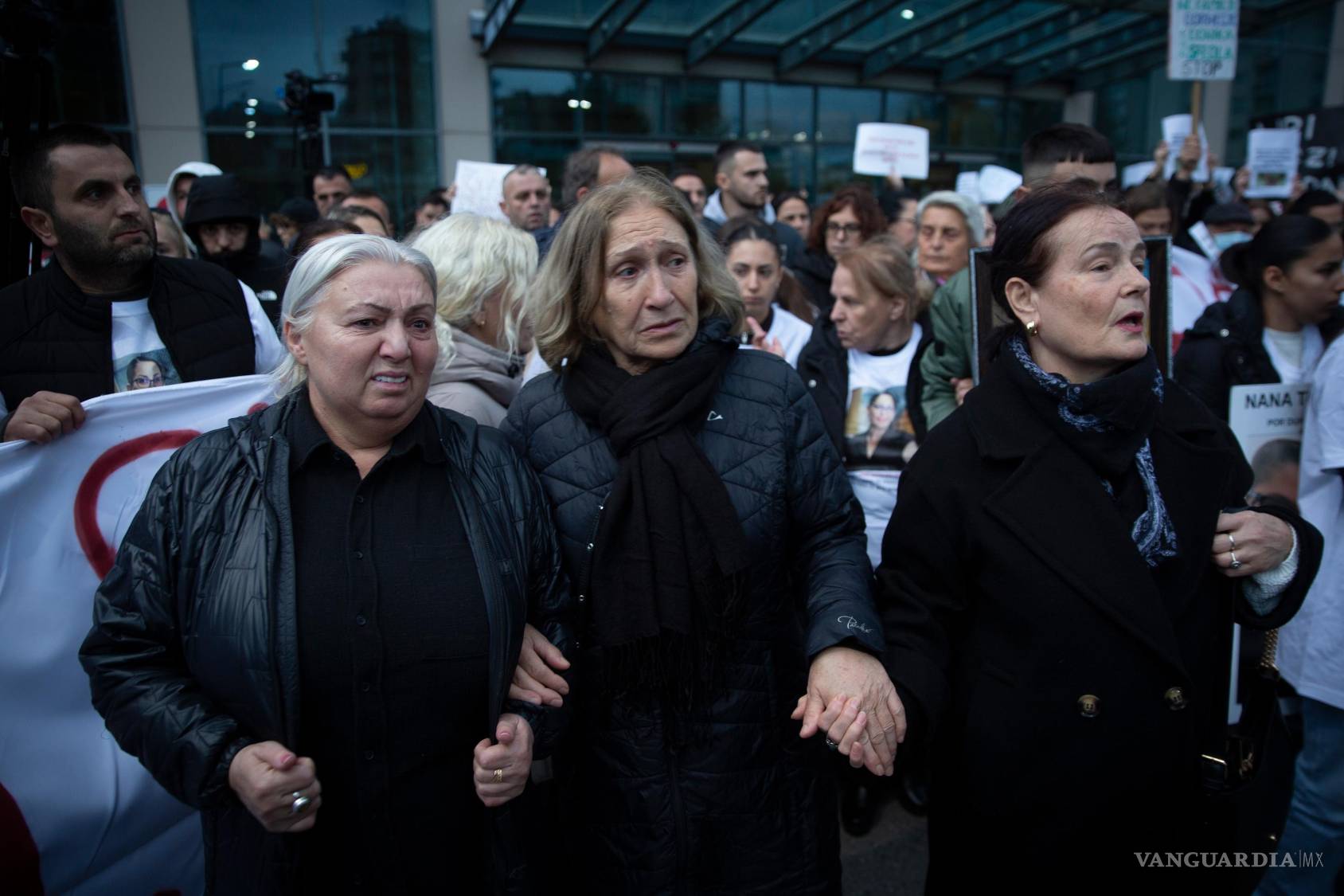 $!Familiares de Arlinda Zekaj se toman de la mano durante una protesta en Pristina, Kosovo, mientras miles de personas se reúnen para condenar el asesinato de esta mujer kosovar-estadounidense