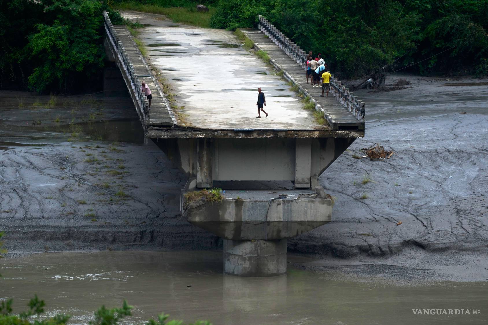 $!Un grupo de personas permanece sobre los restos de un puente que cruzaba el río Trishuli y fue arrastrado por una crecida repentina, en el distrito de Dhading, Nepal, el domingo 30 de agosto de 2026.