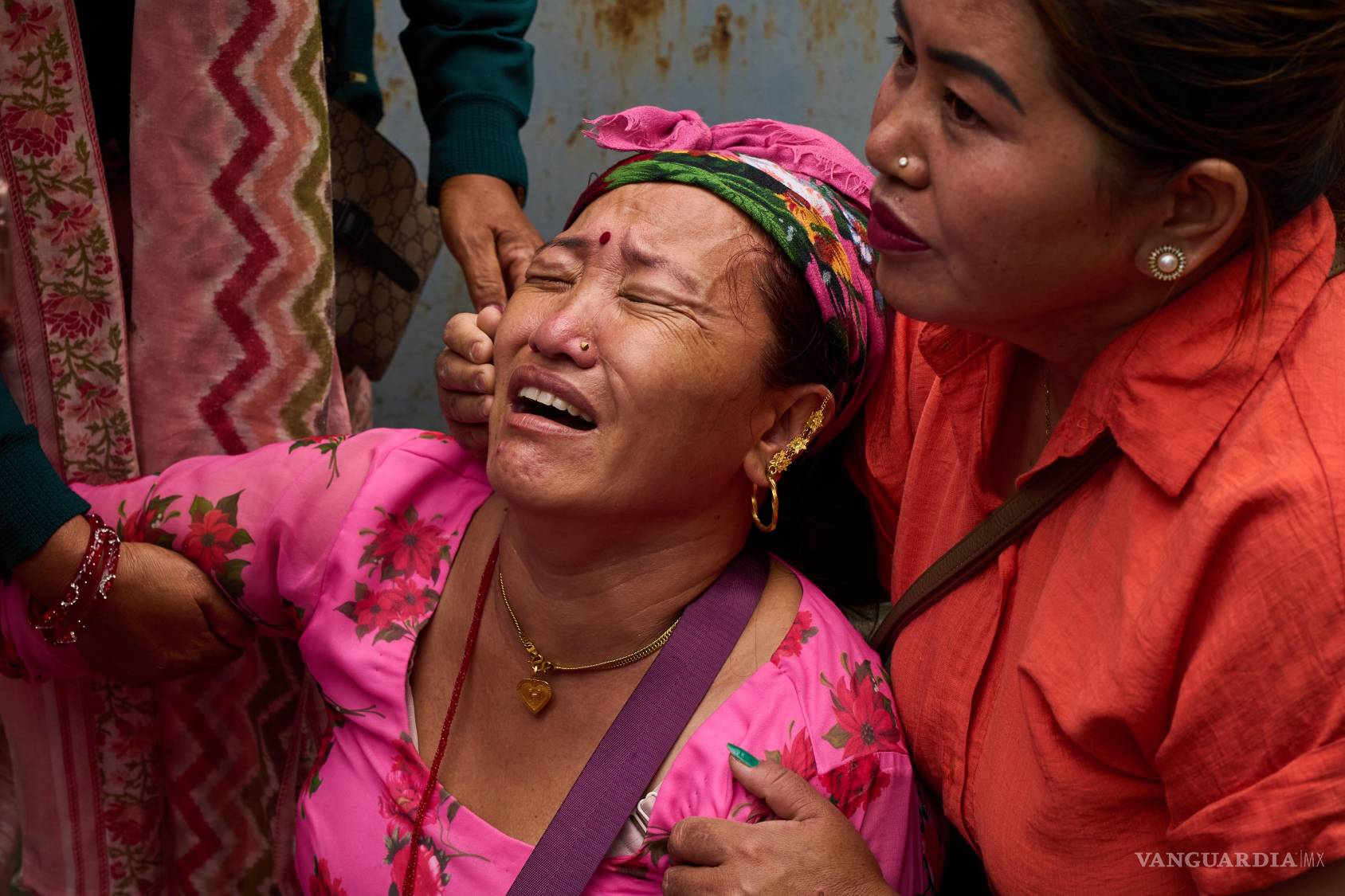 $!Unos familiares consuelan a Jantari Gurung —cuyo esposo está desaparecido— mientras ella observa fotografías de personas fallecidas en inundaciones repentinas, expuestas a las afueras de un hospital público en Katmandú, Nepal, el domingo 30 de agosto de 2026.