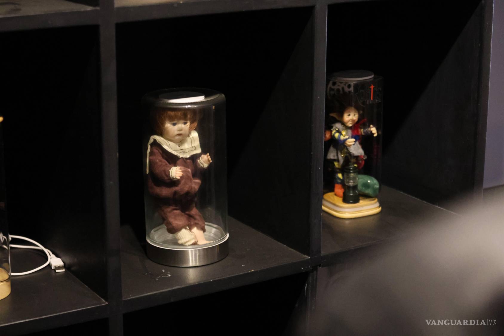 $!Dos muñecas exhibidas bajo cubiertas transparentes evocan uno de los motivos recurrentes del imaginario del terror: los juguetes infantiles convertidos en personajes de relatos inquietantes.