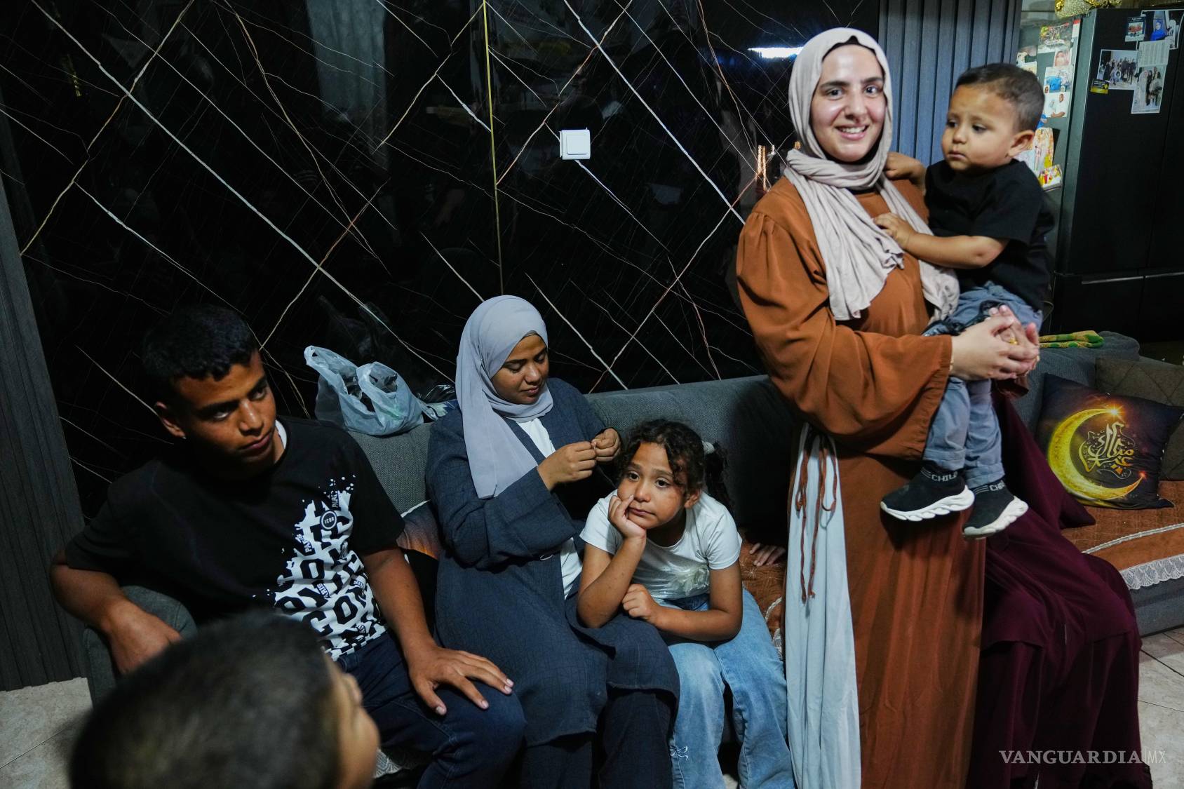 $!Mais Al-Gharam sostiene a su hijo en brazos junto a sus hermanos de Gaza, a quienes se les concedieron pasaportes israelíes, en su casa en Nazaret, Israel, el 8 de julio de 2026.