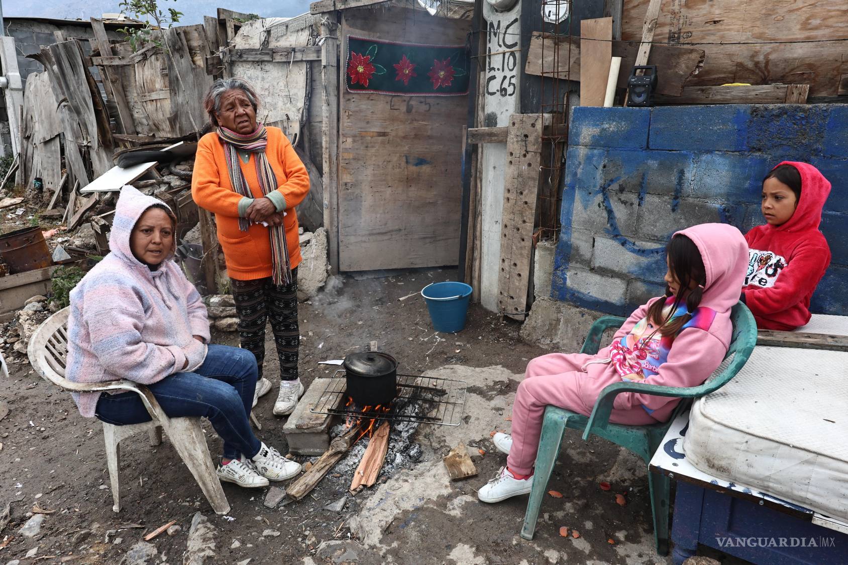 $!Hombres, mujeres y niños se reunieron alrededor del fuego para calentarse, luego de una noche en la que el aire helado se coló por puertas y techos improvisados.