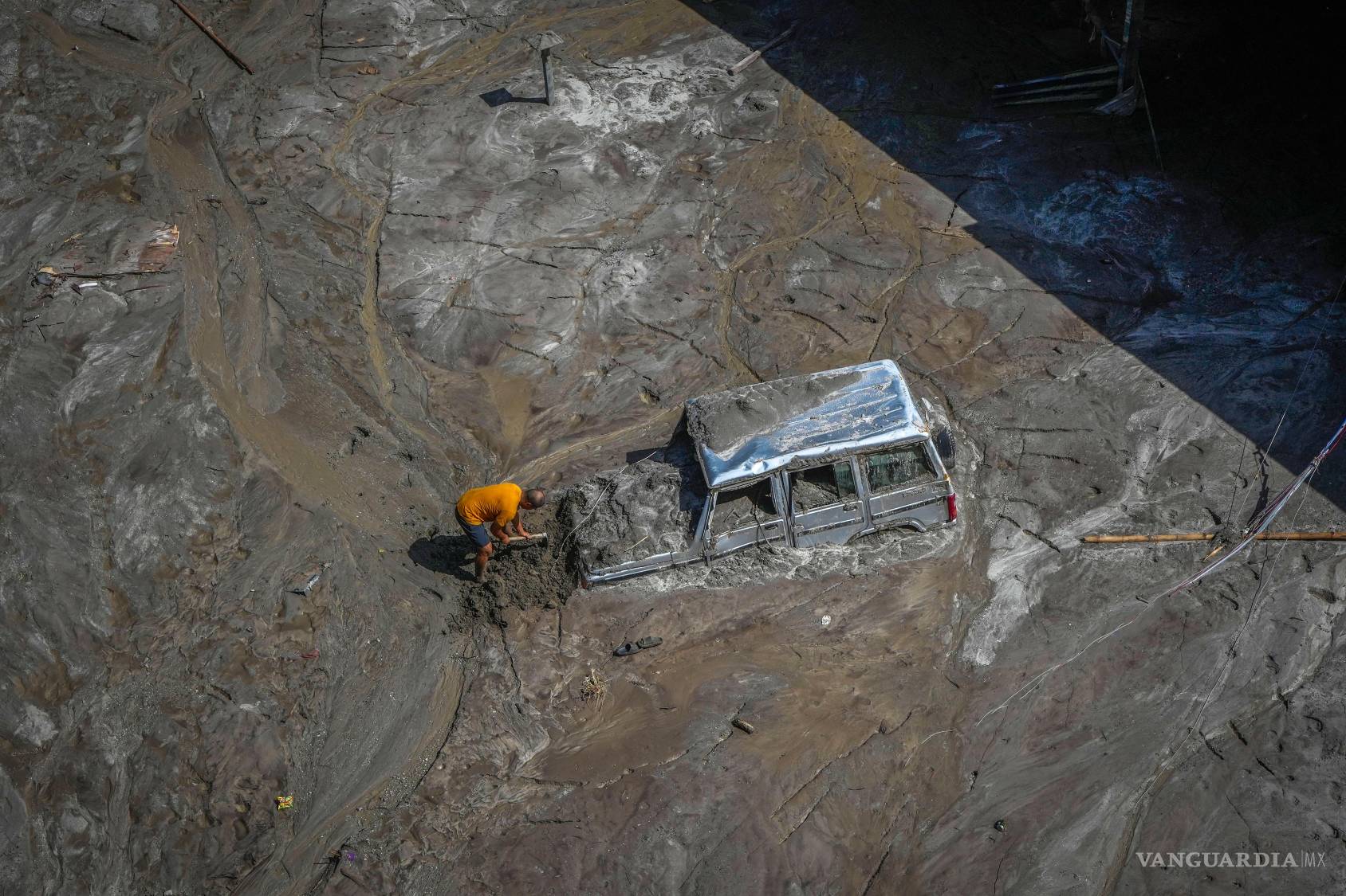 $!Un hombre trata de recuperar un vehículo cubierto de lodo en una zona afectada por una inundación a lo largo del río Teesta, India, el 8 de octubre de 2023.