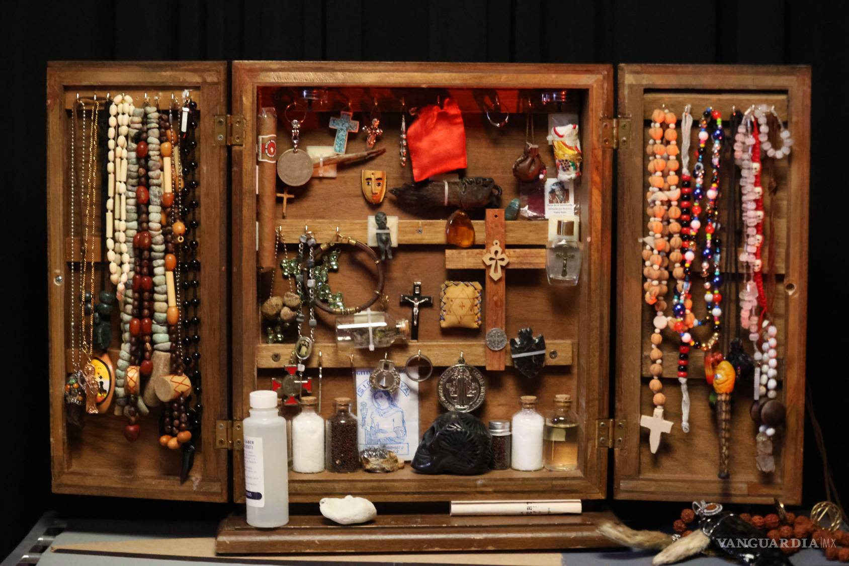 $!Cruces, medallas, collares, recipientes y distintos amuletos conviven en un gabinete donde se reúnen símbolos de diversas tradiciones religiosas y esotéricas.