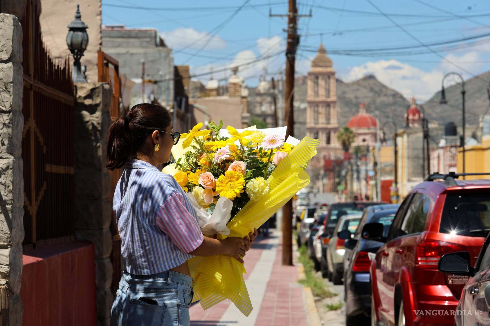$!Una persona porta un arreglo de flores amarillas sobre la calle Juárez, con la majestuosa Catedral de Santiago de fondo.