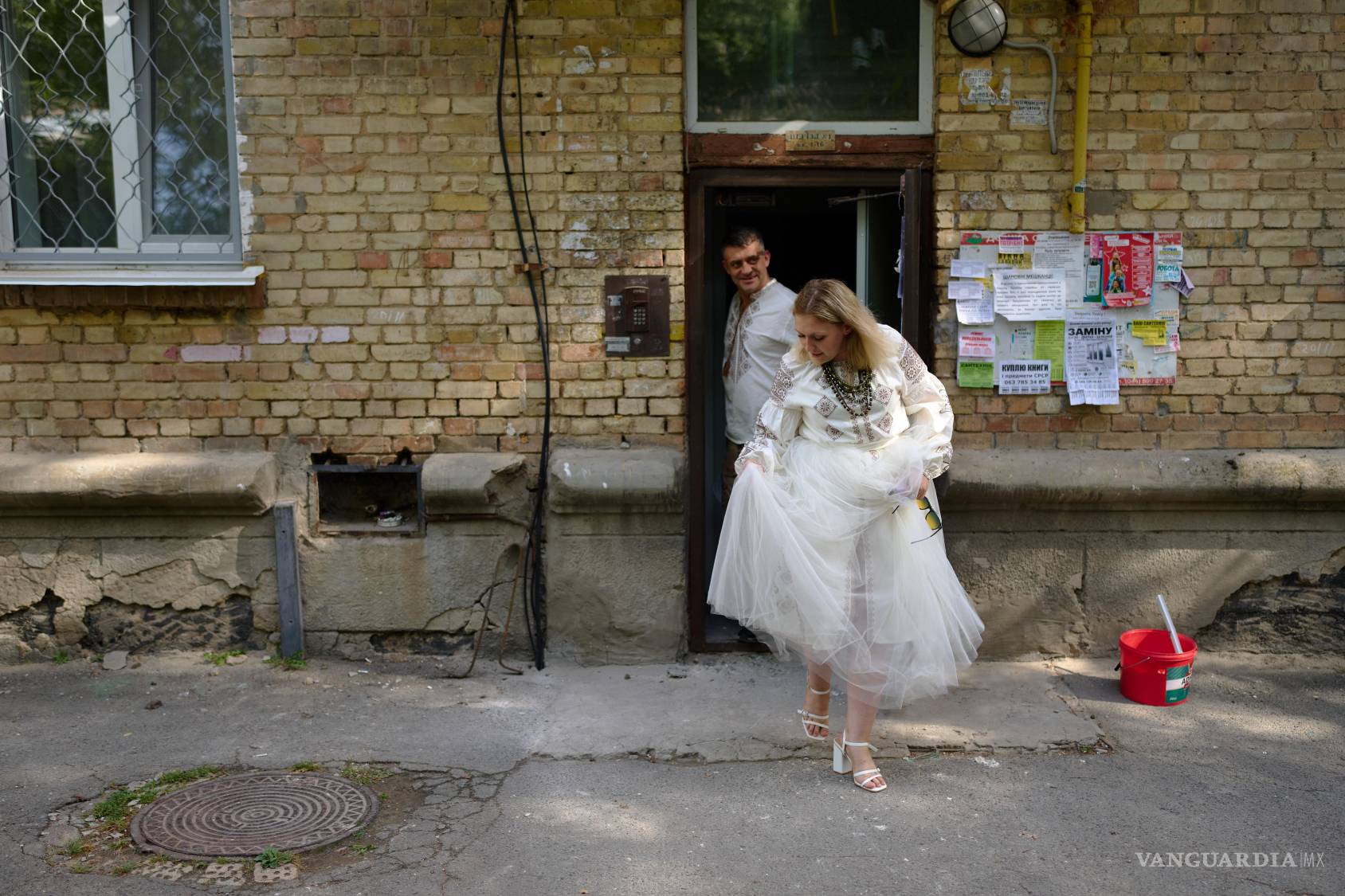 $!Liudmyla Ryzhak y su prometido, Leonid Ryzhak, salen de un edificio residencial dañado para dirigirse a su ceremonia de boda en Kiev, Ucrania.