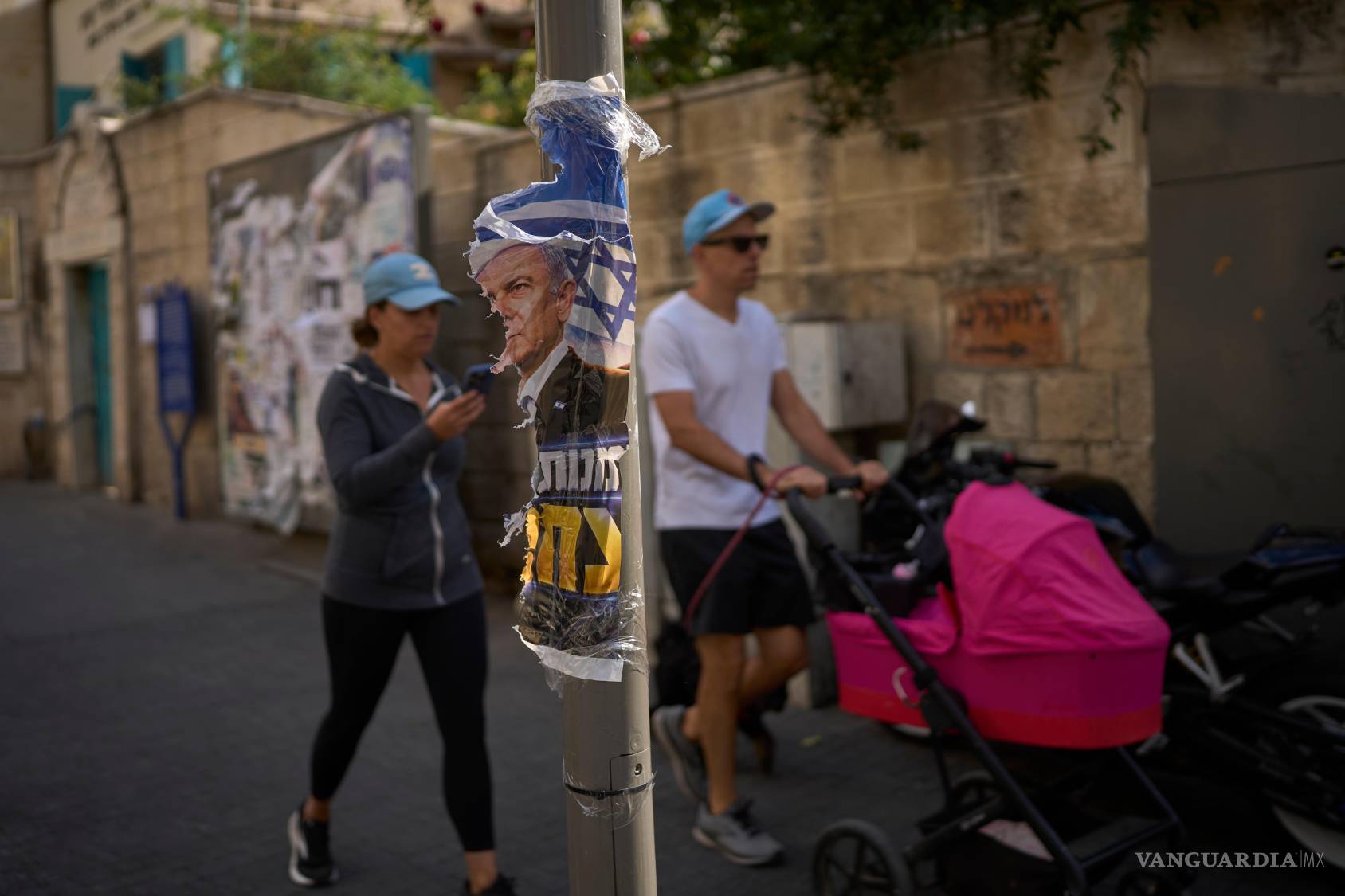 $!Un hombre y una mujer caminan junto a un cartel rasgado del primer ministro israelí, Benjamin Netanyahu, en Jerusalén, un día después de las elecciones.
