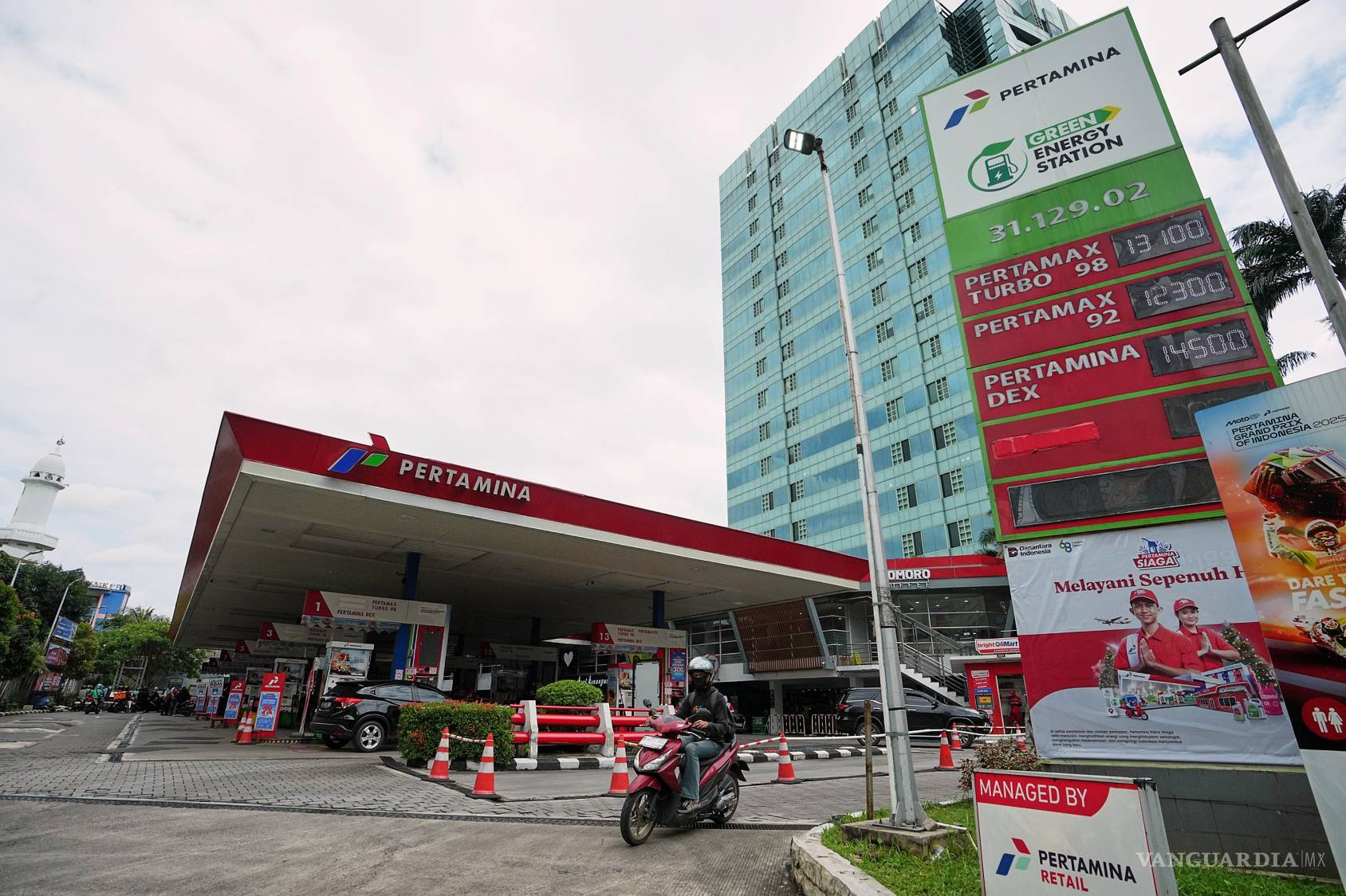 $!Un automovilista pasa frente a una gasolinera donde se muestran los precios del combustible en Yakarta, Indonesia.