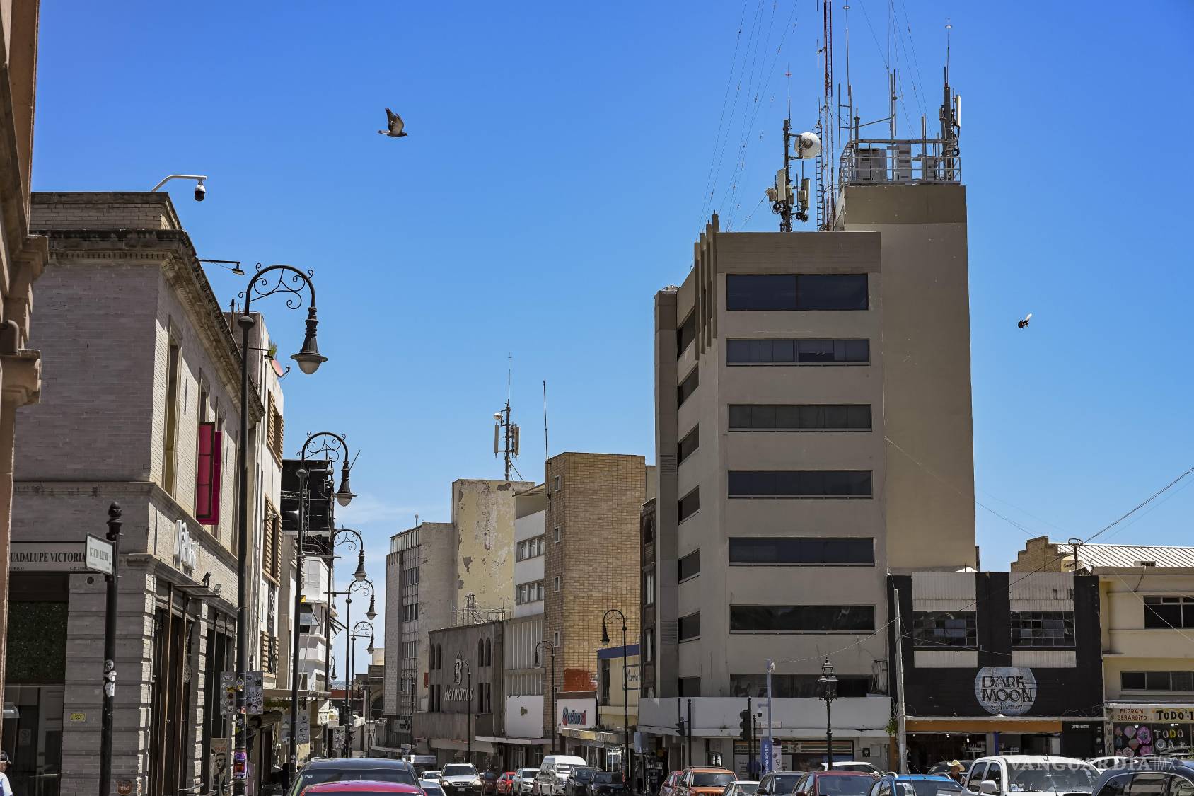 $!Vista de sur a norte, la calle Allende muestra cómo los edificios de distintas épocas conviven sobre una planta baja dominada por comercios, tránsito y anuncios. La ciudad vertical sigue ahí, pero para verla hay que mirar por encima de la circulación cotidiana.