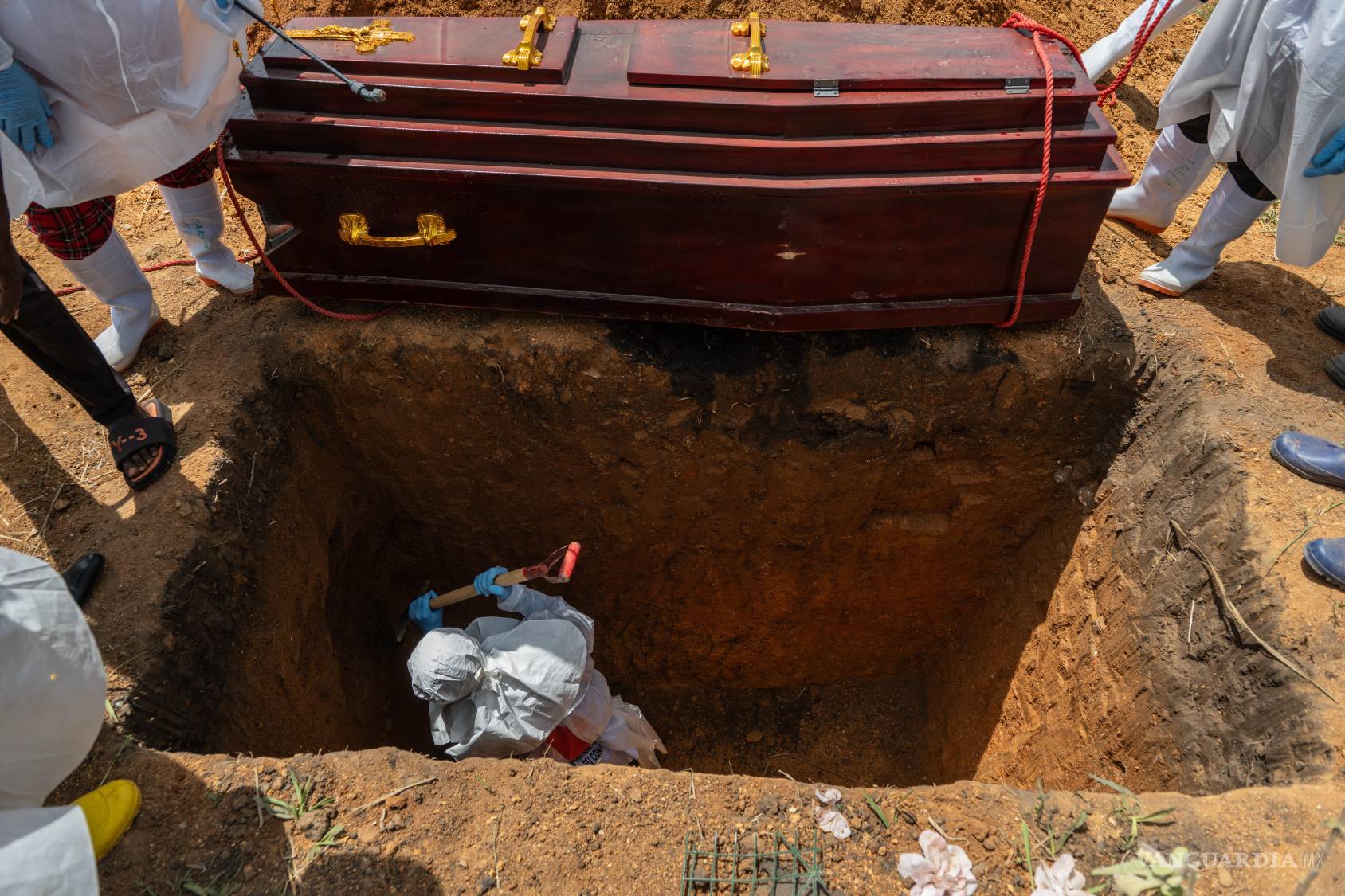 $!Trabajadores de la Cruz Roja entierran a una víctima del ébola en el cementerio de Rampara, en Rwampara, Congo.