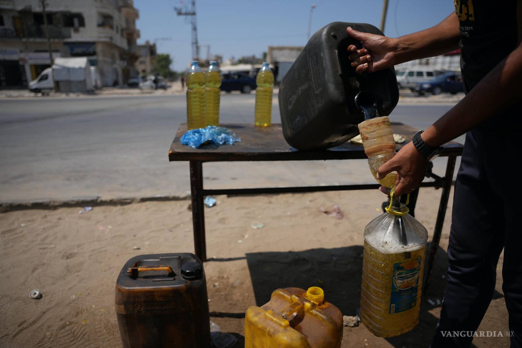 $!Un vendedor palestino rellena botellas con combustible en su puesto en el campo de refugiados de al-Maghazi, en el centro de la Franja de Gaza.