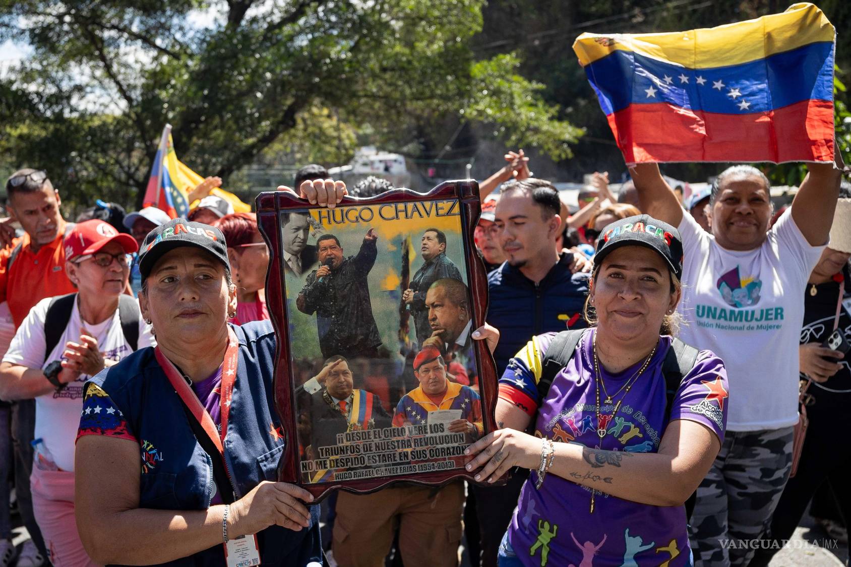 $!Personas sostienen un cuadro con imágenes del presidente fallecido Hugo Chávez durante una marcha del chavismo en Caracas, Venezuela.