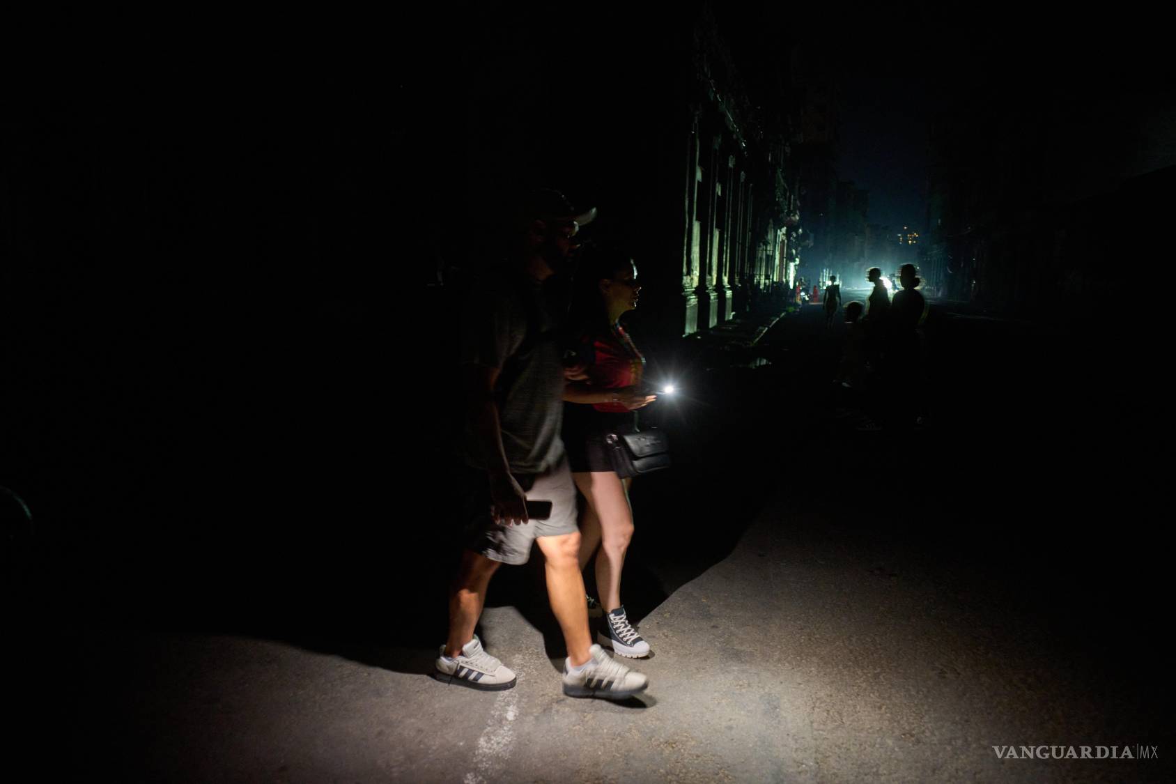 $!Varias personas caminan por una calle iluminadas con linternas durante un apagón en La Habana, Cuba, el lunes 6 de julio de 2026.