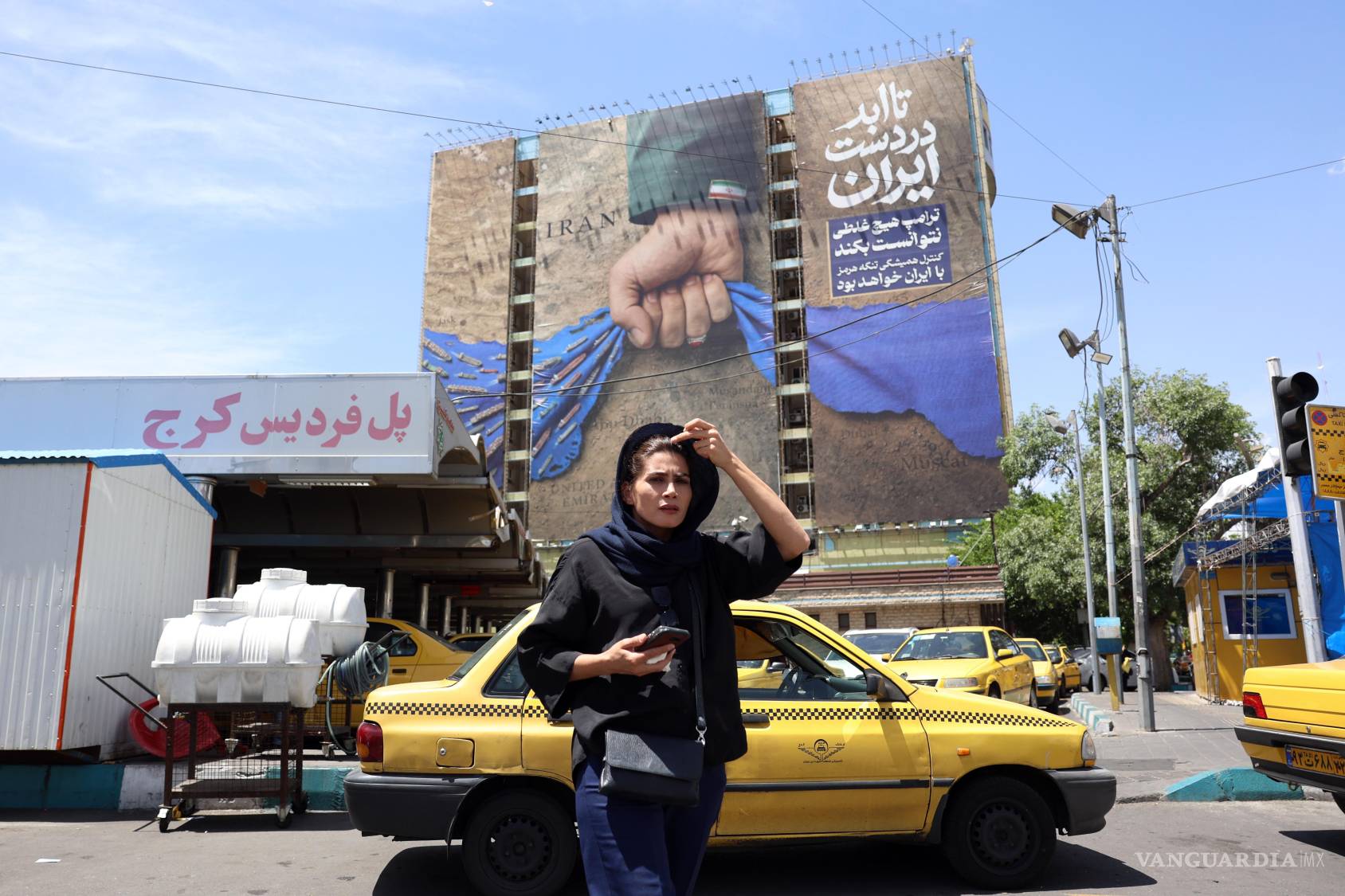 $!Mujer iraní camina cerca de una enorme valla publicitaria que hace referencia al estrecho de Ormuz y a las palabras en persa «Siempre en manos de Irán» en la plaza Vanak de Teherán, Irán.