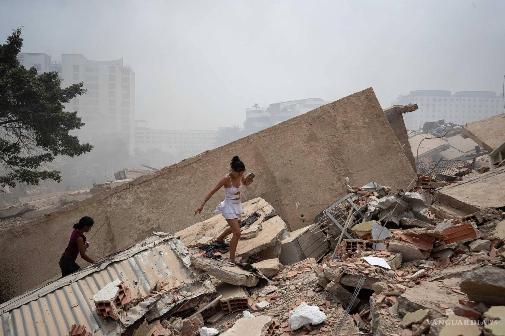 $!Personas caminan este jueves, entre los escombros de edificios afectados por los terremotos en La Guaira, Venezuela.