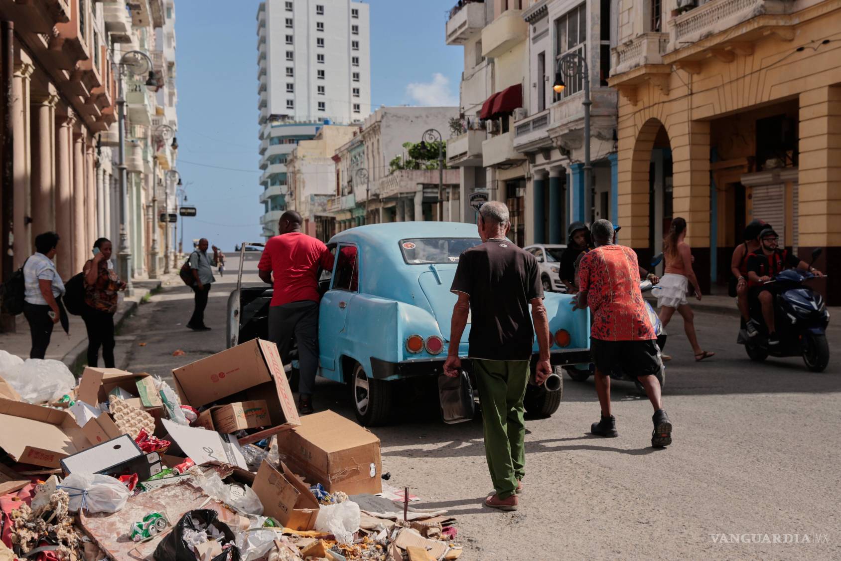$!Varias personas empujan un coche clásico americano averiado junto a un montón de basura en La Habana, Cuba.