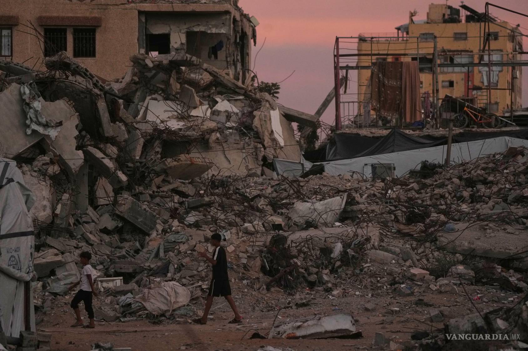$!Palestinos caminan por una calle rodeada de edificios destruidos por los ataques militares israelíes en la ciudad de Gaza, el martes 6 de octubre de 2026.