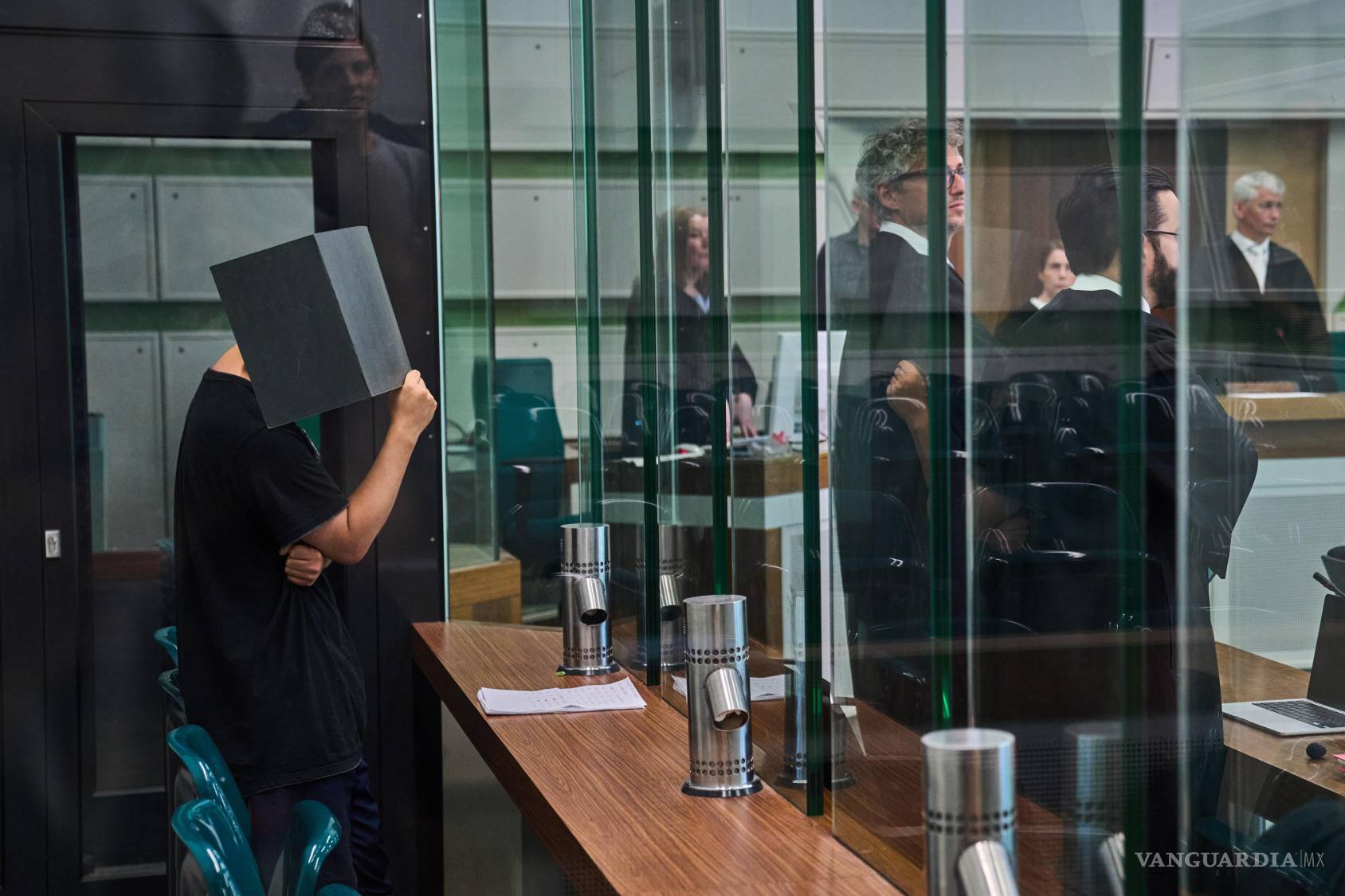 $!Un acusado se cubre el rostro en la sala del tribunal durante un juicio contra una red de depredadores sexuales en línea en Berlín, Alemania