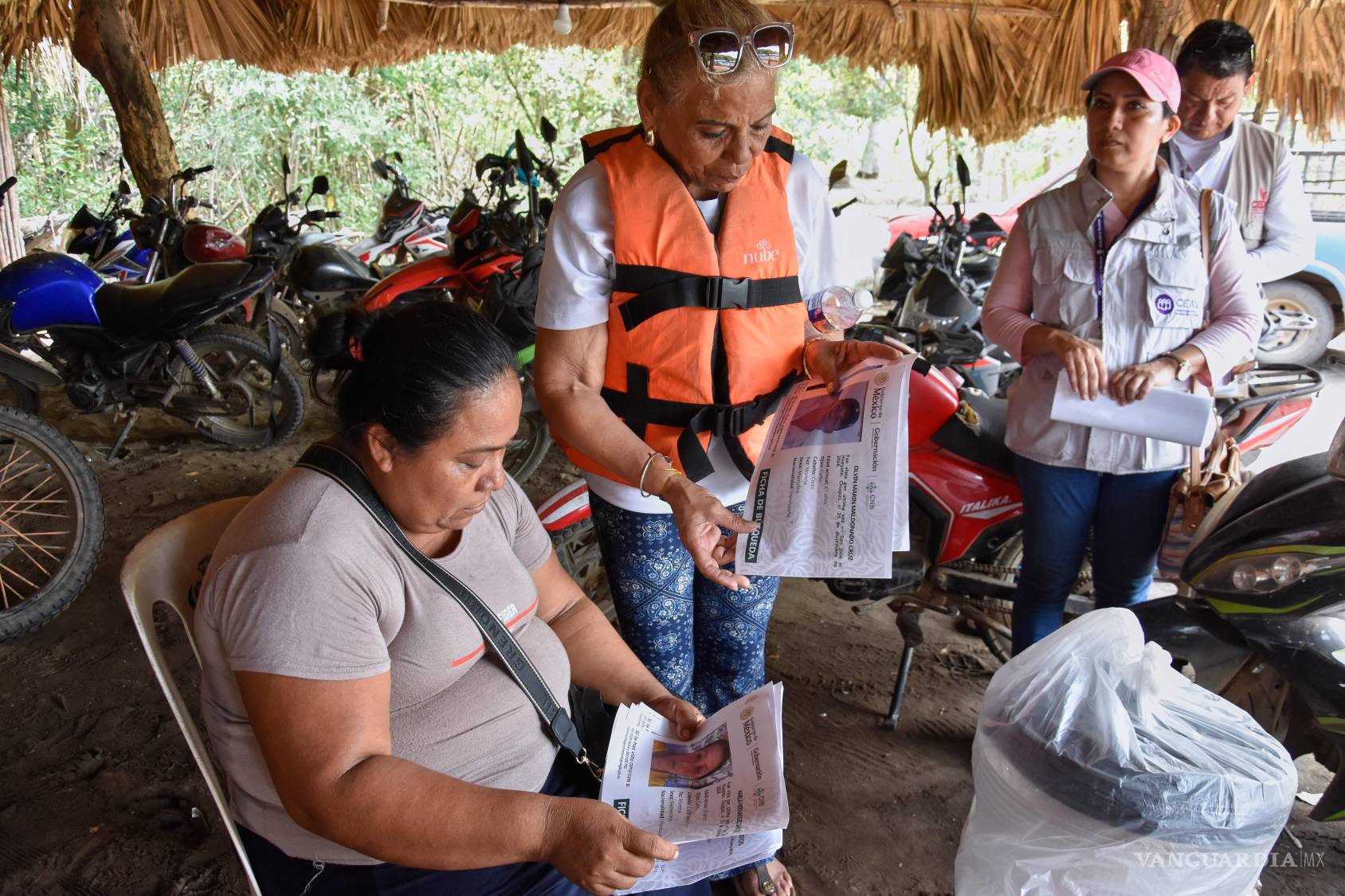 $!La cubana Julia Margarita Bravo Díaz, con chaleco salvavidas, muestra fotos de personas desaparecidas, incluyendo a su hija Meiling Álvarez Bravo y su nieto.