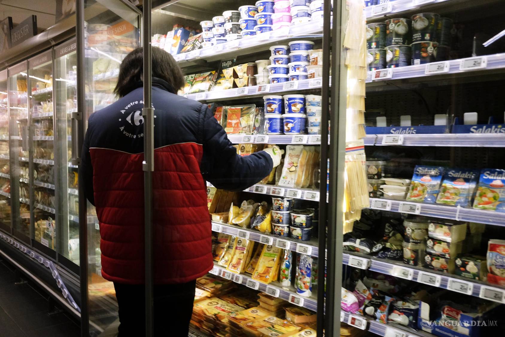 $!Un trabajador reabastece productos en la sección refrigerada de un supermercado dos días después del ciberataque a varios supermercados franceses en Montreuil.