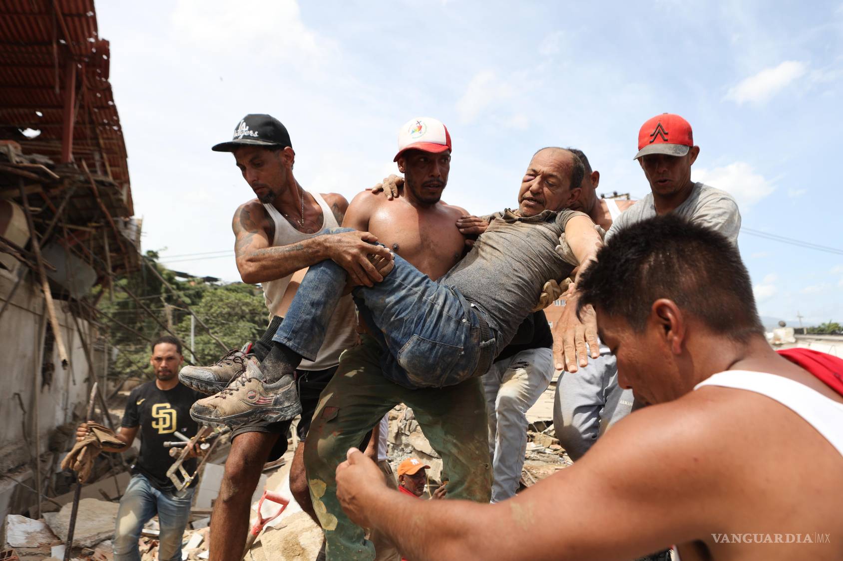 $!Vecinos transportan a un hombre rescatado de entre los escombros de un edificio derrumbado al día siguiente de los terremotos que azotaron La Guaira, Venezuela.