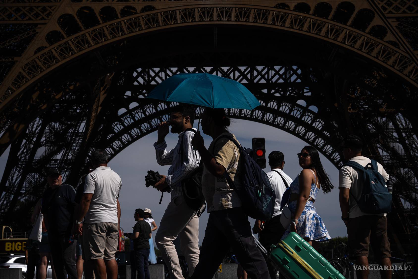 $!Personas caminan con paraguas cerca de la Torre Eiffel, en París, durante una ola de calor el 11 de julio de 2026.