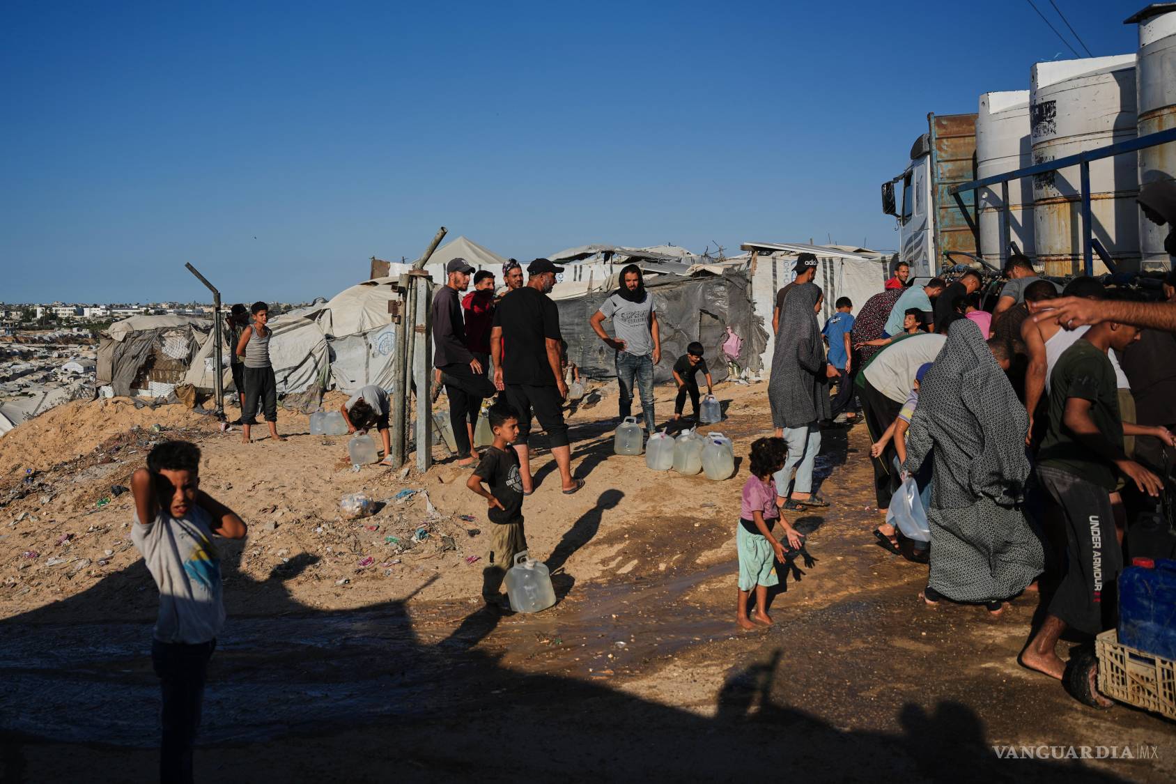$!Palestinos desplazados se reúnen para recoger agua potable de un proveedor en Deir al-Balah, en el centro de la Franja de Gaza, el miércoles 7 de octubre de 2026.