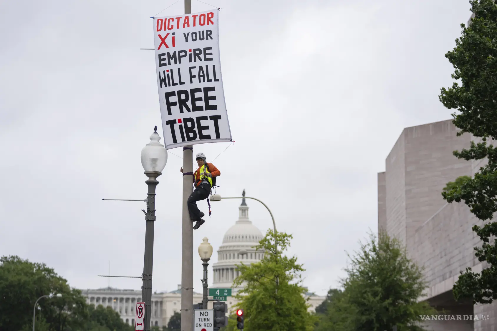 $!Un manifestante trepa a un poste y despliega una pancarta para protestar contra la próxima visita de Estado del presidente chino Xi Jinping en Washington.