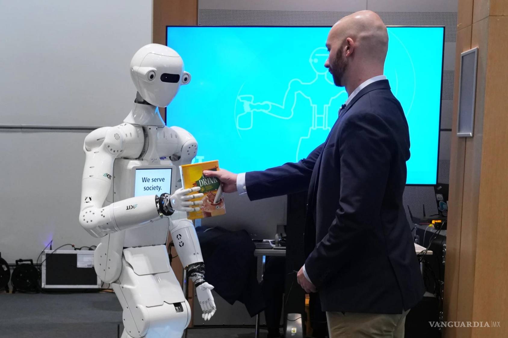 $!Un hombre recibe una caja de bebida de chocolate de manos de un robot durante una demostración de robótica basada en IA en el Parlamento Europeo de Bruselas.
