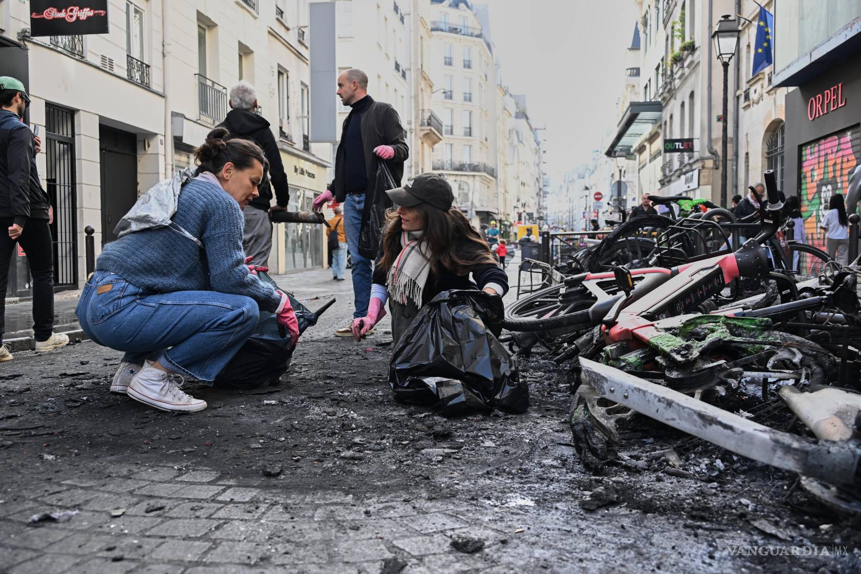 $!Varias personas recogen escombros en una calle, junto a bicicletas quemadas, un día después de una manifestación en París, el domingo 18 de octubre de 2026.