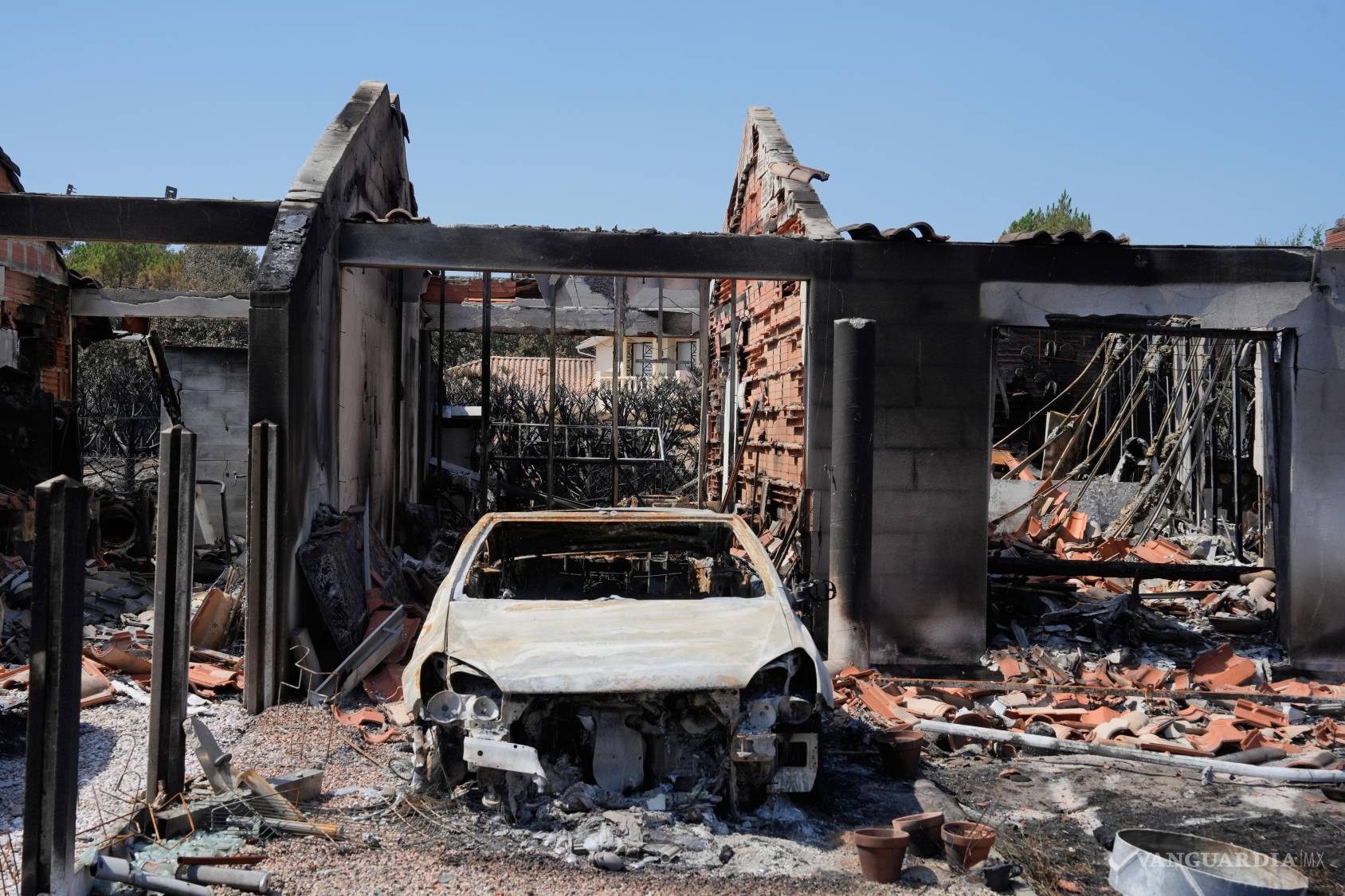 $!Un automóvil calcinado y los restos de una casa tras incendios forestales que azotaron el pueblo de Le Porge, e Vizcaya, Francia, el 27 de julio de 2026.