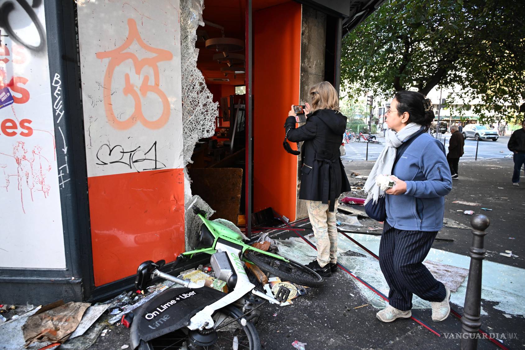 $!na mujer toma una instantánea de una tienda saqueada, al día siguiente de una manifestación en París contra el aumento del costo de la vida.