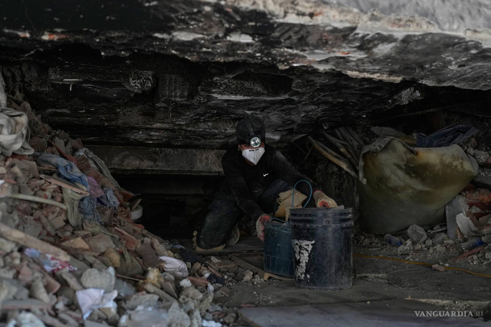 $!María Morales saca dos cubos de escombros mientras excava en un edificio derrumbado por los terremotos, en busca de su tía Yaeina Vera, en La Guaira.