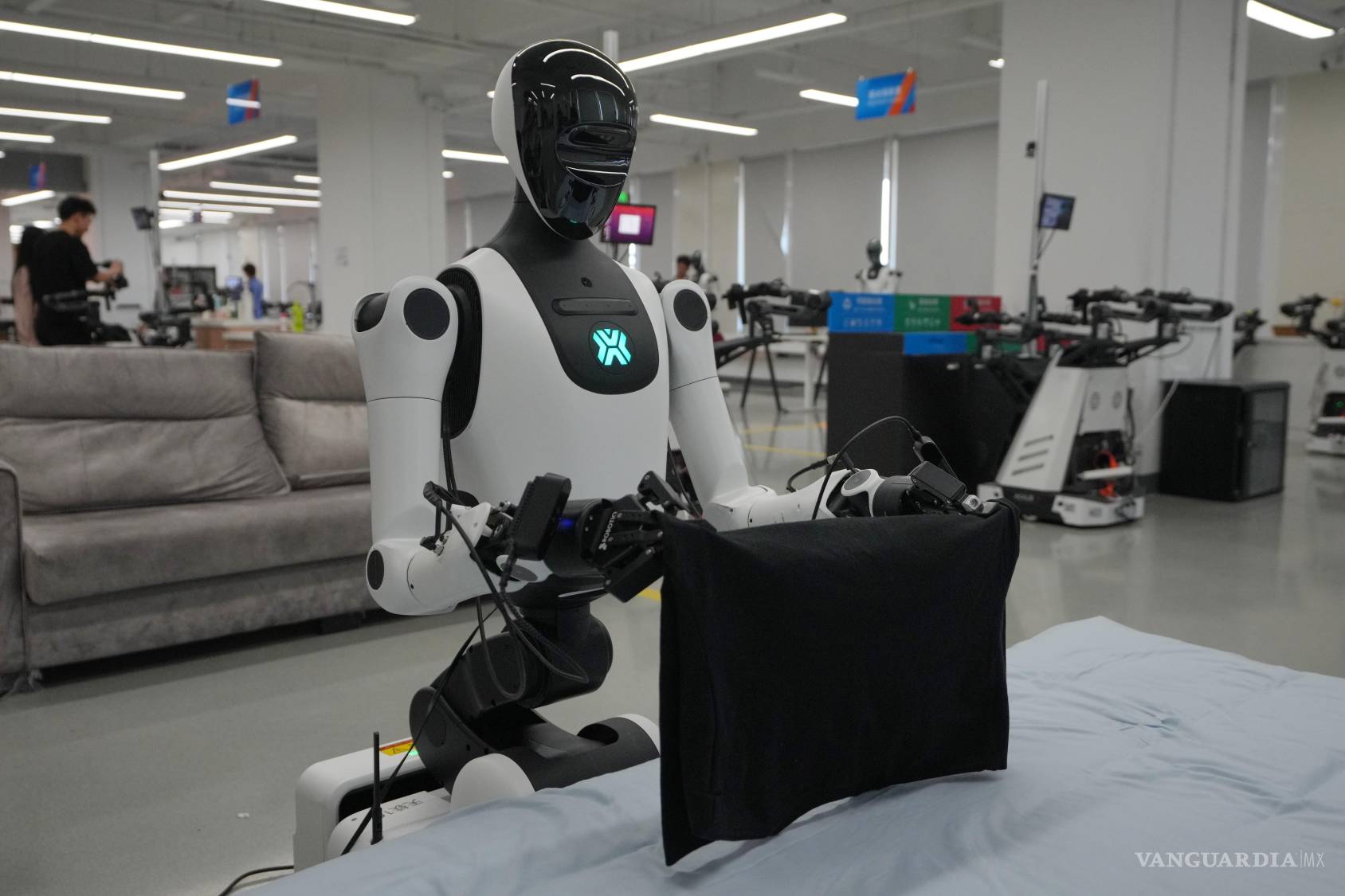 $!173Un robot doblando ropa en una cama en la Base de Datos y Entrenamiento de Robots de IA durante una visita de prensa en la Ciudad Electrónica de Pekín.