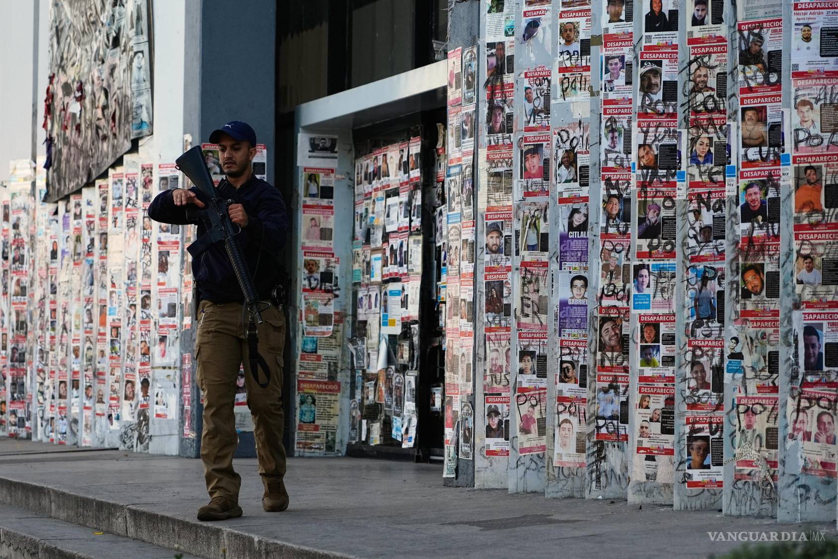 $!Un agente de policía pasa por delante de una pared cubierta con carteles con el rostro de desaparecidos en Guadalajara, Jalisco.