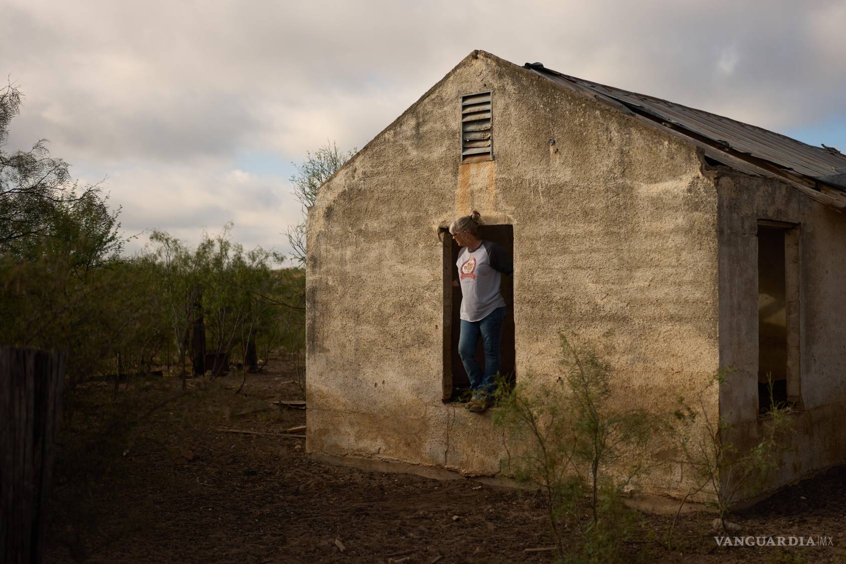 $!Laura Allen permanece en el hueco de una ventana de una antigua casa de rancho mientras espera a su esposo en su propiedad en Comstock, Texas.