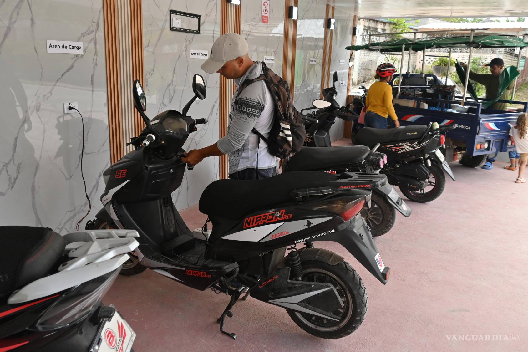 $!Giraldo Lázaro Perez Paret, que trabaja en el sector del turismo, recarga su motocicleta eléctrica en Santa Clara, Cuba.