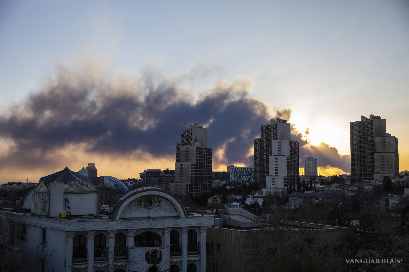 $!El sol se pone mientras una nube de humo de los ataques aéreos cubre el cielo de Teherán, el martes 3 de marzo de 2026.