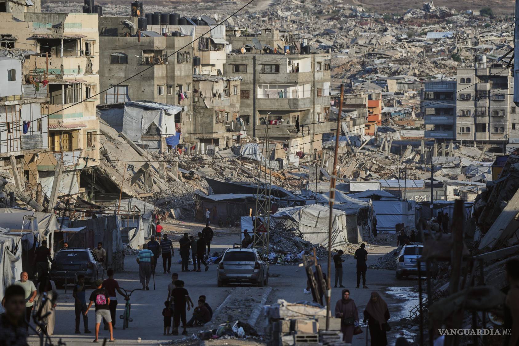 $!Palestinos caminan por una calle rodeados por edificios destruidos por ataques militares israelíes durante la guerra en Israel y Hamás en Ciudad de Gaza.
