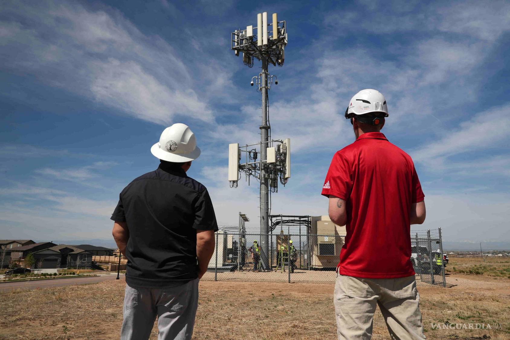 $!Trabajadores observan una torre donde están instaladas las cámaras Pano AI para la detección de incendios forestales en Aurora, Colorado.