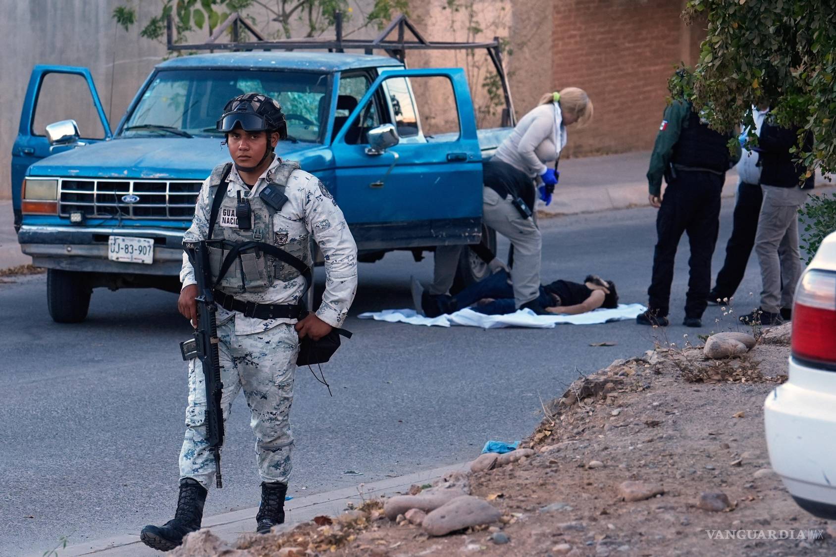 $!Un miembro de la Guardia Nacional vigila mientras expertos forenses inspeccionan el lugar donde se encontró el cuerpo de una víctima en Culiacán.