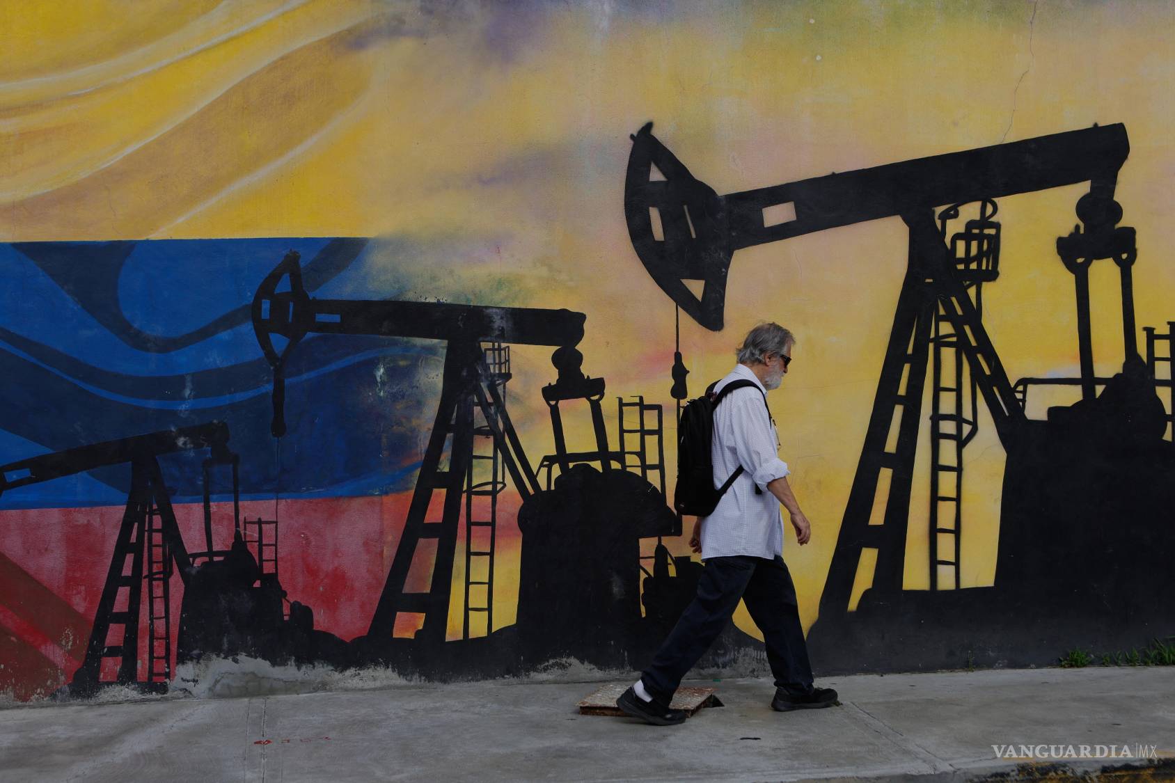 $!Un peatón pasa frente a un mural de pozos petroleros en Caracas, un día después de que Trump anunciara un acuerdo que otorga a EU una participación en las reservas de petróleo de Venezuela.