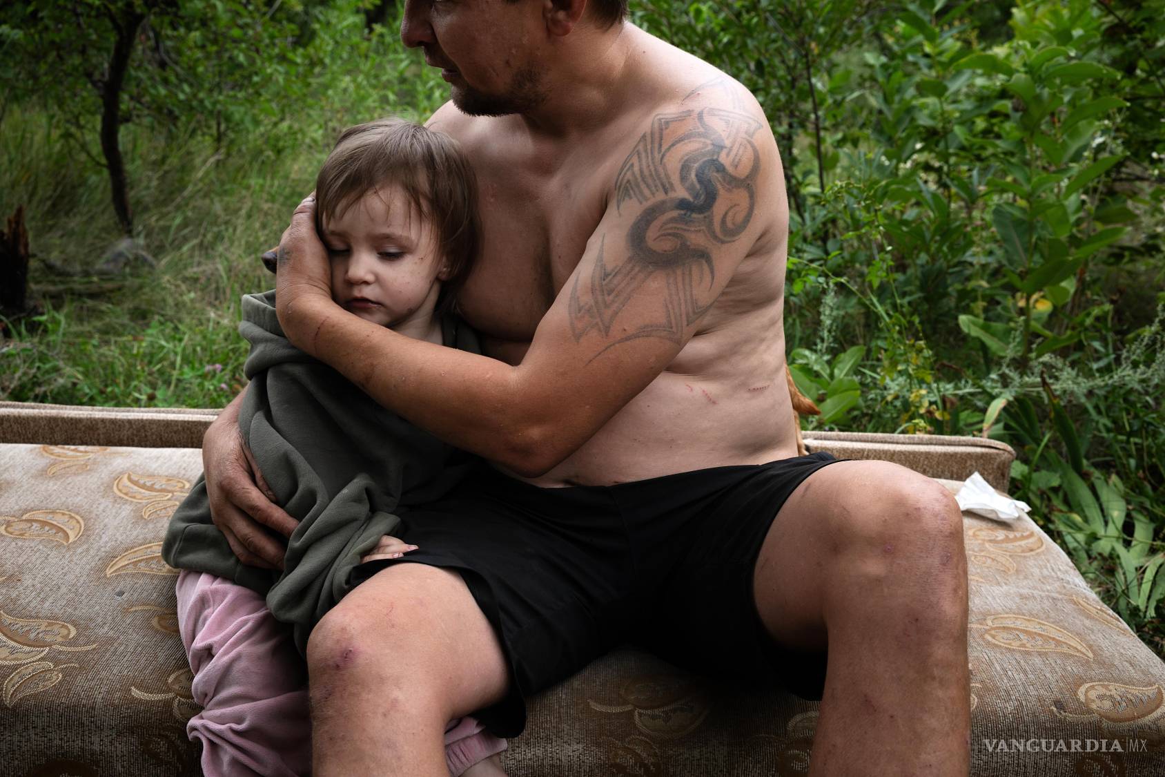 $!Un padre consuela a su hija en una zona boscosa tras huir rápidamente a un lugar seguro al recibir una alerta de ataque aéreo ruso en Sloviansk, Ucrania.
