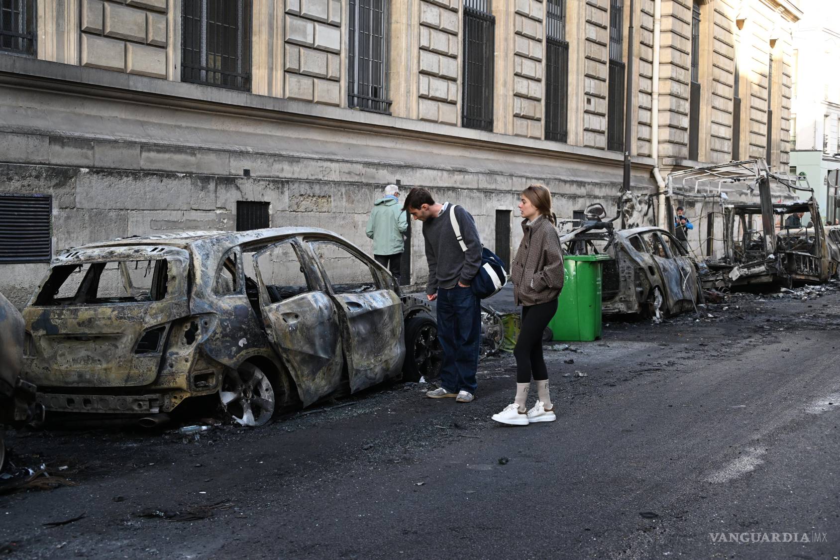 $!Dos personas observan un coche calcinado cerca de la plaza de la República, al día siguiente de una manifestación en París, Francia.