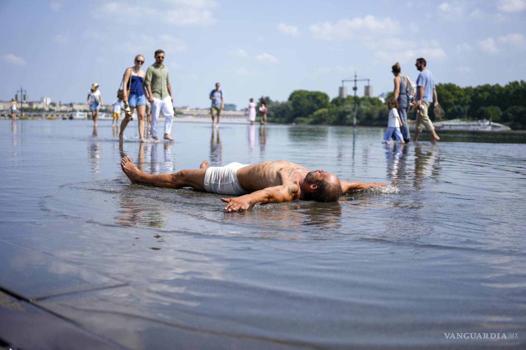 $!Varias personas aprovechan para refrescarse en una fuente en frente de la plaza de la Bolsa de Burdeos, al suroeste de Francia.
